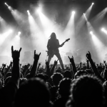 Black-and-white rock concert seen from the crowd, with a guitarist performing under stage lights